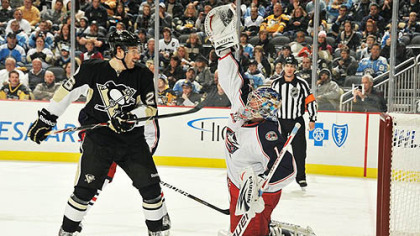 Blue Jackets goaltender Steve Mason reaches up to snag the puck off a shot as Penguins forward Eric Tangradi looks for a rebound during Tuesday's game at Consol Energy Center.