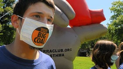 Colin Van Bortel-Buckley of Oakland, a junior at the University of Pittsburgh who has asthma, stands in front of an 18-foot-tall inflatable hand holding an inhaler in Schenley Park on Wednesday to spotlight health risks from coal-fired power plants.