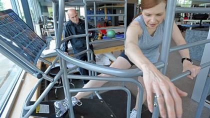 Leslie Rubinkowski stretches her hamstrings as Ron DeAngelo, director of Sports Performance, looks on at UPMC's Indoor Training Center.
