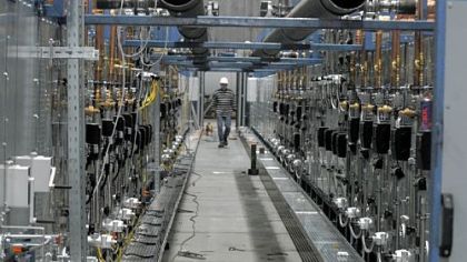 A worker walks between two ovens lined with copper tubing where the glass will be made for parabolic solar mirrors at Flabeg Solar US in the Clinton Commerce Park in Findlay Township.