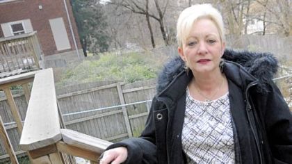 Colleen Walters stands on the steps leading to the back deck of her McNeilly Road home in Dormont. In the background is a vacant property with a backyard overtaken by bamboo.