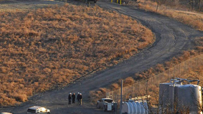 Officials huddle near a compression station in Mount Pleasant, Washington County, after a worker early Tuesday morning reported smoke coming from the facility.