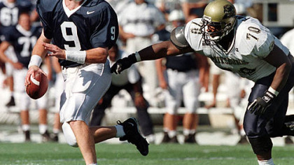Penn State quarterback Mike McQueary is chased by Pitt defensive lineman Frank Moore during a game at Beaver Stadium in University Park, Pa. Sept. 6, 1997. The schools have not met in football since 2000.
