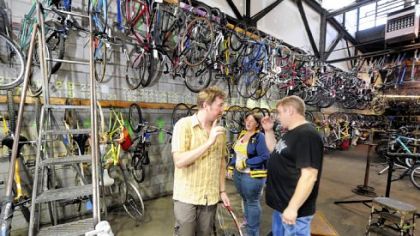 Volunteer John McNamara, left, helps Jessica and Scott Woodstuff look for a bike.