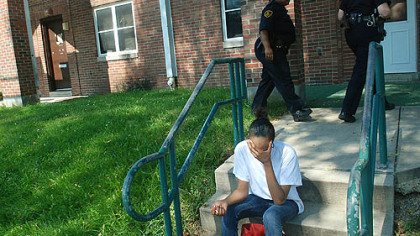 Kendra Jackson, who said she is a sister of the shooting victim, sits on a stoop on Chauncey Drive on Monday as police officers search for information.