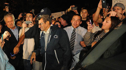 A large group of students and others surround Penn State football head coach Joe Paterno at his home.