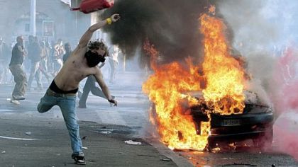 A protestor hurls a canister towards police next to a burning car Saturday in Rome. Protesters smashed shop windows and torched cars as violence broke out during a demonstration in the Italian capital, part of worldwide protests against corporate greed and austerity measures, entitled Occupy Wall Street.