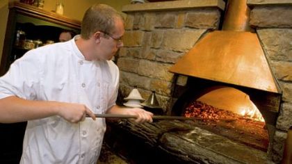 Chef Tom Wurst tends to the wood-burning oven, a centerpiece of the kitchen at Bado's Cucina in Peters.