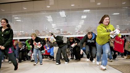 Black Friday shoppers duck under the opening door of a Sears store at Simon Property Group Inc.''s Great Lakes Mall in Mentor, Ohio, U.S., on Friday, Nov. 25, 2011. Black Friday, traditionally the biggest U.S. shopping day of the year, got off to its earliest start ever as retailers tried to woo shoppers with discounts and early store openings.