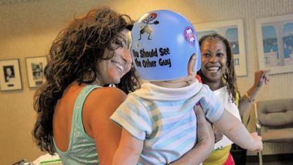 Jocelyn Corcoran (left) and April Blue, who works at Union Orthotics & Prosthetics, play with Jocelyn's son, Braylon, who wears a helmet to help correct a flat spot on his head.