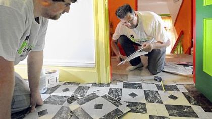 Andrew Deshler, left, and his father, Ed, put down new flooring in Sandra Ford's Race Street home.