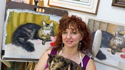 Bernadette Kazmarski, an animal portrait artist who created "Great Rescues," a calendar that features portraits of cats, in her home studio in Carnegie with her 19-year-old cat, Cookie.