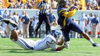 West Virginia receiver Tavon Austin tries to elude Connecticut defender Dwayne Gratz in the first half Saturday at Mountaineer Field in Morgantown, W.Va