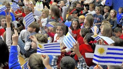Waving their Uruguayan flags during an assembly, Howe Elementary students welcome two fifth-grade students and their teacher, who have been pen pals.