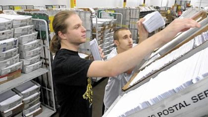 Chris Harris, left, and Caleb Miller hustle to put mail sorted by a multiple-line optical character reader at 30,000 pieces per hour into flats for delivery to the post office.