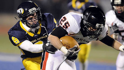 Upper St. Clair's A.J. McGuire carries as he's defended by Central Catholic's Leo Loughery last night.