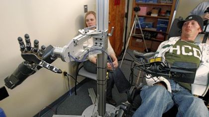 Assistant professor Jennifer Collinger, left, watches as quadriplegic research subject Tim Hemmes operates the mechanical prosthetic arm in a testing session at UPMC.