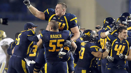 West Virginia's Hunter Bittner leaps onto teammate Tyler Rader after defeating Pitt last night, 21-20.