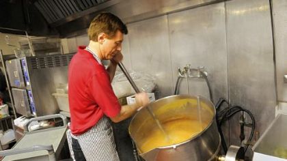 Jim Calato stirs a steam-jacketed kettle of gravy in preparation for the annual Thanksgiving lunch at the City Deli.