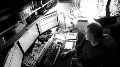 Tom Alberts sits in front of his computer array, where he spends about 20 hours a week working as a freelance Web designer.