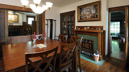 The dining room features a decorative fireplace with forest green tile and a hefty oak mantelpiece.
