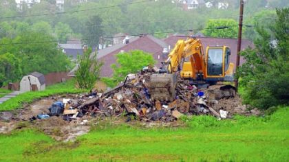 A backhoe sits atop rubble remains of a recently demolished house just west of Buckhannon Pike in Clarksburg, W.Va.