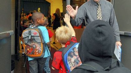 George Washington Elementary principal Paul Sweda gives high-fives to students Thursday as they arrive for the first day of school.