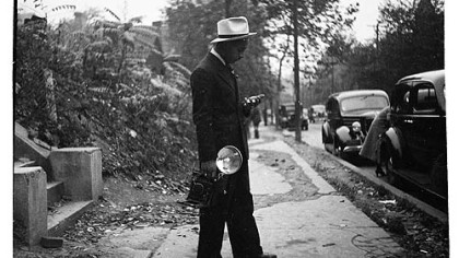 Teenie Harris, holding camera and standing on sidewalk, c. 1938.
