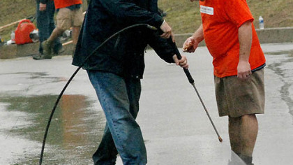 Keith Todd, left, of Foremost Groups, a Home Depot vendor, blasts the mud off the shoes of John Prentice, a Home Depot store manager in North Fayette, after Mr. Prentice had finished his landscaping work at the Southwestern Veterans Center on Highland Drive in Lincoln-Lemington on Wednesday.