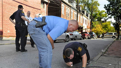 Pittsburgh Police detective John Rouse and Pittsburgh Police officer Jason Hall look in a sewer for a gun that was used in a Monday morning shooting at the corner of Armandale Street and Brighton Road on the North Side.