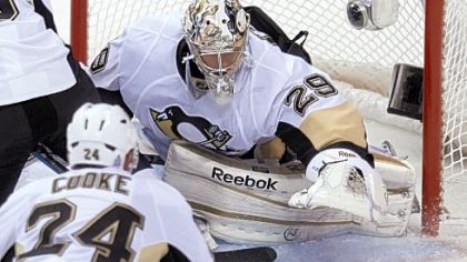 Goalie Marc-Andre Fleury reaches down to smother the puck as Matt Cooke looks on in the second period Thursday in the season opener against Vancouver.