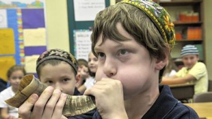 A fourth-grader at Community Day School demonstrates blowing the shofar, which will be done during Rosh Hashana services around the world after the holiday begins at sundown tonight.