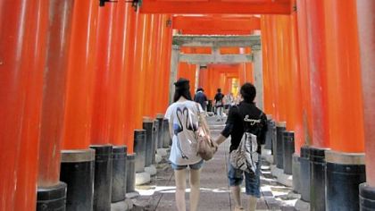Visitors to Fushimi-Inari Taisha pass under thousands of orange gates en route to a shrine near Kyoto, Japan.