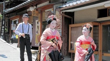 Maiko, geishas in training, are sought after by tourists for photos as they walk through Kyoto.